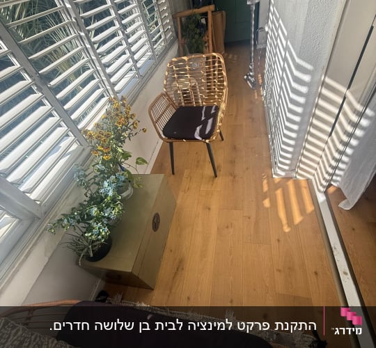 רצפת פרקט עם כיסא ופרחים ליד חלון